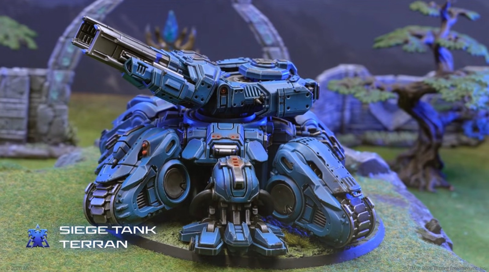 A painted Terran Siege Tank miniature in blue armor on a grassy battlefield.